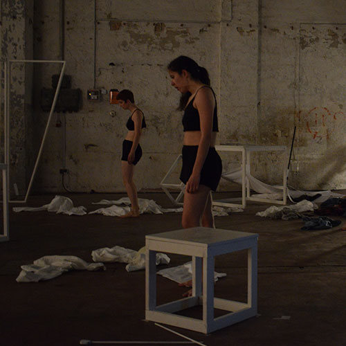 Performers Elly Rutherford and Violeta Valcheva are standing amids the ruins of the dream city
